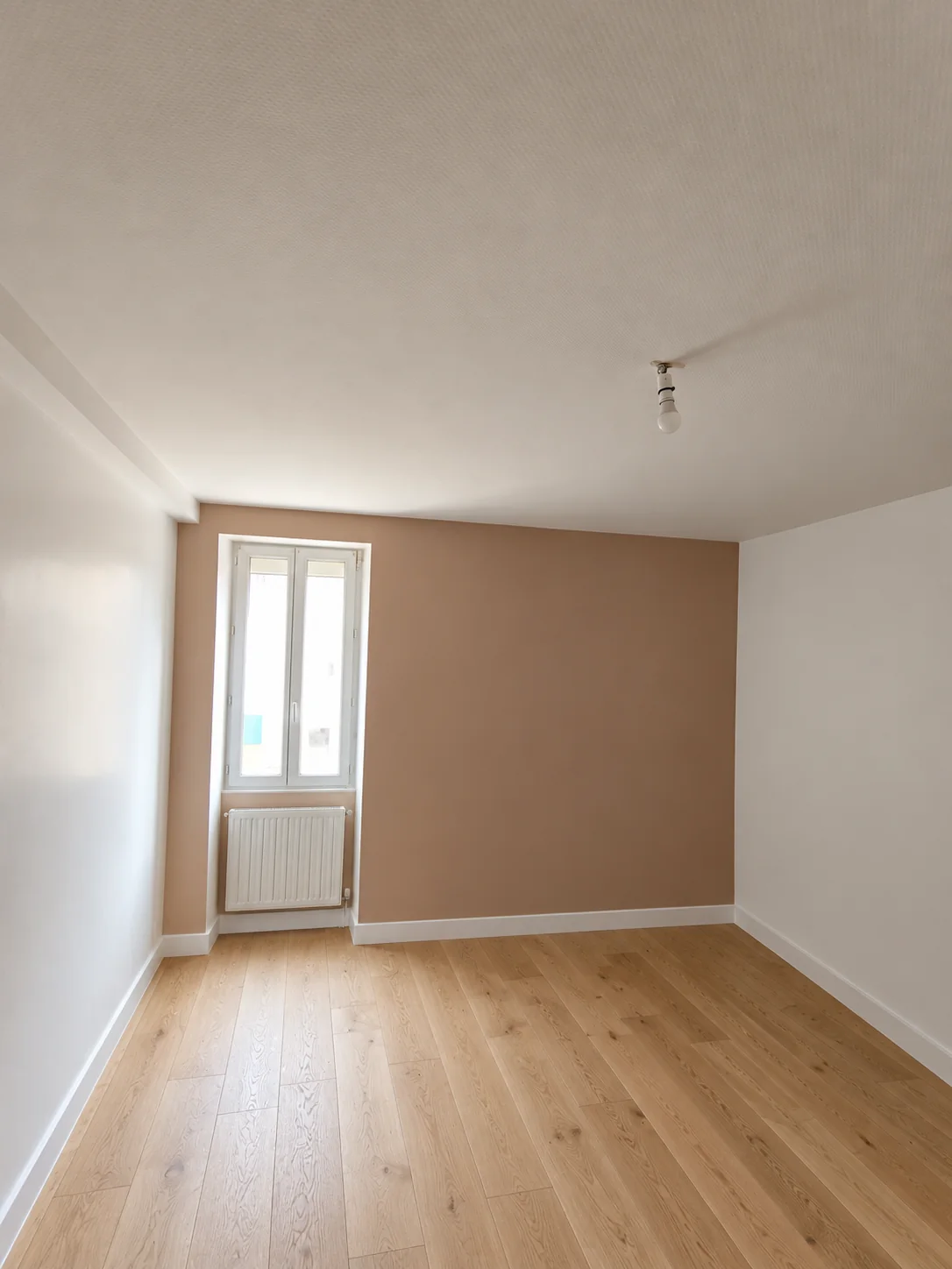 Chambre avec un mur couleur terre et un sol en bois